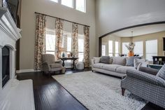 a living room with couches, chairs and a rug on the floor in front of a fireplace