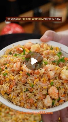 someone holding a plate full of fried rice with shrimp