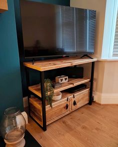 a flat screen tv sitting on top of a wooden entertainment center next to a window