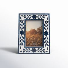 a blue and white photo frame with flowers on the border, in front of a plain background