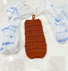 an orange crocheted bag sitting on top of a table next to plastic bags