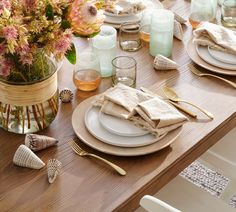 the table is set with plates, silverware and flowers