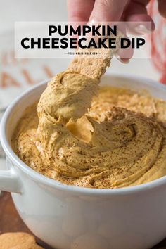 pumpkin cheesecake dip in a white bowl with a hand holding a cracker over it