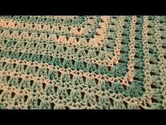 a crocheted green and beige blanket on top of a bed