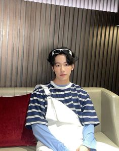 a young man sitting on top of a couch next to a red pillow