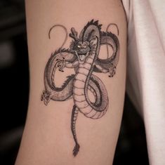 a black and white photo of a dragon tattoo on the arm with an evil face