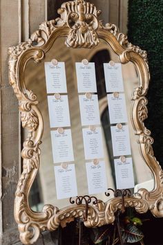 a gold framed mirror with seating cards on it