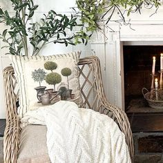 a wicker chair sitting in front of a fireplace with candles on the mantel