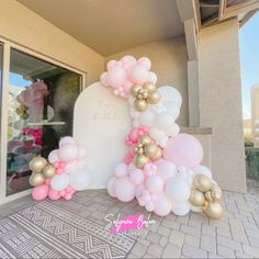 a balloon arch is decorated with pink, gold and white balloons