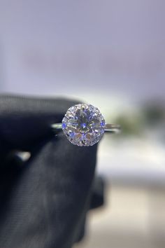 a close up of a diamond ring on someone's finger with the background blurry