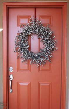 a red door with a metal wreath on the front and side doors, which are decorated with silver balls