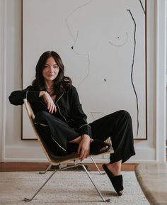 a woman sitting on a chair in front of a painting