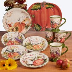 a table topped with plates and cups filled with fall decorations next to a vase full of flowers