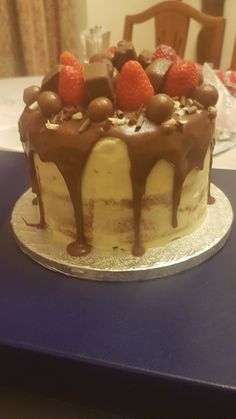 a cake with chocolate icing and strawberries on top sitting on a blue table