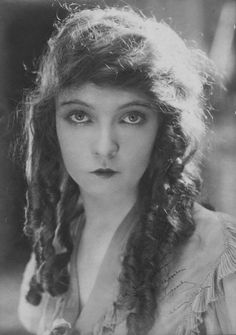 an old black and white photo of a woman with braids on her hair, looking at the camera