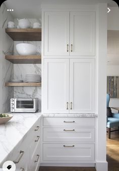 a kitchen with marble counter tops and white cabinets, along with open shelving units