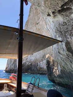 a boat is in the water next to a large rock formation with an umbrella over it's head