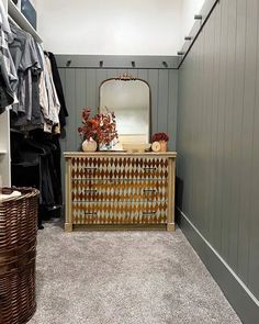 a closet with a dresser, mirror and clothes hanging on the wall next to it