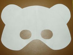 a white mask with two holes in the middle on a brown surface next to a pair of scissors