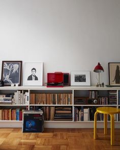 there are many bookshelves in the room with pictures on each shelf and a yellow chair next to them