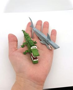 a hand is holding two toy alligators and an airplane