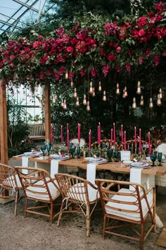 an outdoor dining area with tables, chairs and flowers hanging from the ceiling over it