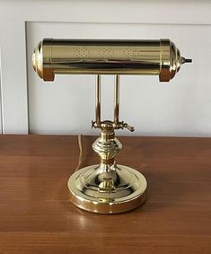 a brass desk lamp sitting on top of a wooden table