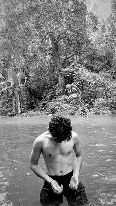 a shirtless man standing in the middle of a river