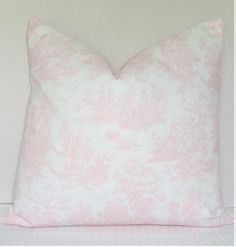 a pink and white pillow sitting on top of a bed