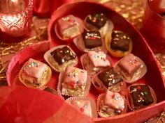 a red box filled with lots of chocolates on top of a table covered in confetti