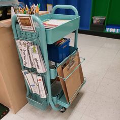 a blue cart filled with lots of papers and folders on top of a tiled floor