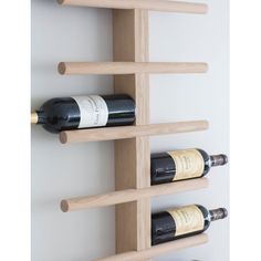 three bottles of wine are sitting on the wall next to each other in a wooden shelf