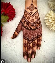 henna tattoo on the palm of someone's hand with flowers in the background