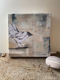 a painting sitting on top of a counter next to a rock and a wire cord