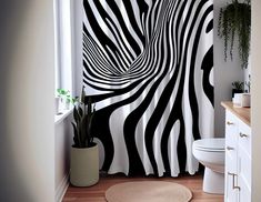 a bathroom with a zebra print shower curtain next to a white toilet and wooden floor