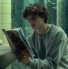 a young man reading a book in the bathroom