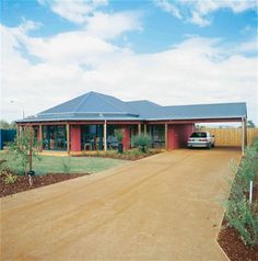 a house with a car parked in front of it on a dirt road next to a fence