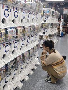 a woman kneeling down in front of a rack of wii remotes at a store