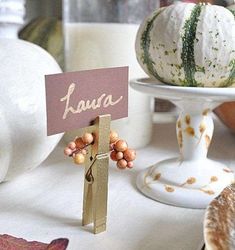 a table topped with white pumpkins and other fall decorating items, including a sign that says kaua