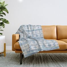 a couch with a blanket on it next to a potted plant