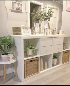 a white shelf with baskets and plants on it