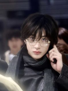 a man in glasses talking on a cell phone while wearing a black jacket and scarf