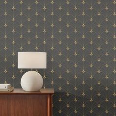 a lamp on top of a wooden table next to a wallpapered wall with an art deco design