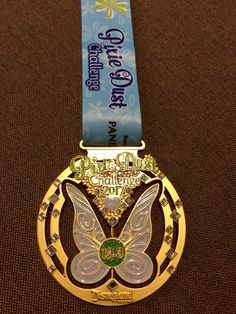 a gold medal with a butterfly on it's neck and a ribbon around it