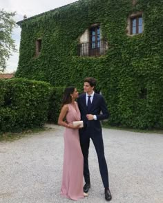 a man in a suit and tie standing next to a woman in a pink dress