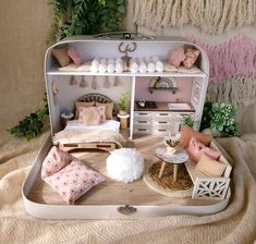 a doll house with furniture and accessories on a bed in front of a wall hanging