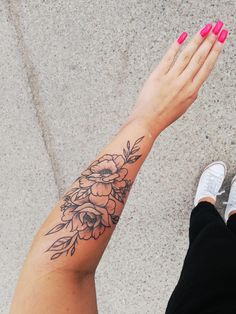 a woman's arm with flowers on it and her hand holding the wrist tattoo