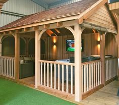 a wooden gazebo sitting on top of a lush green field next to a building