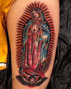 a tattoo on the leg of a person with an image of virgin mary in red and blue