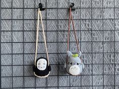 two small crocheted animals hanging from hooks on a wall next to each other